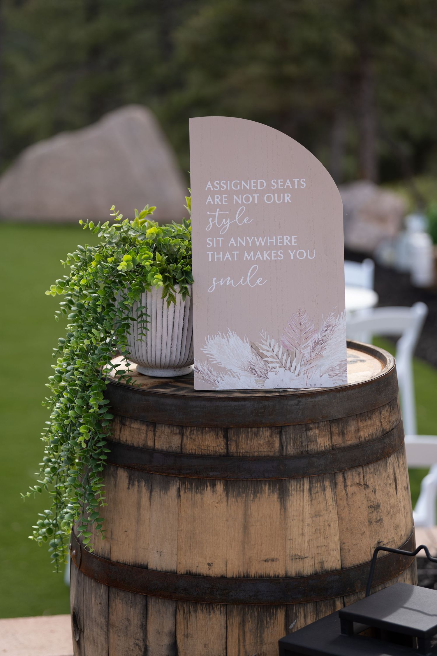 Rustic wooden barrel displays with wedding signage and greenery decorations.