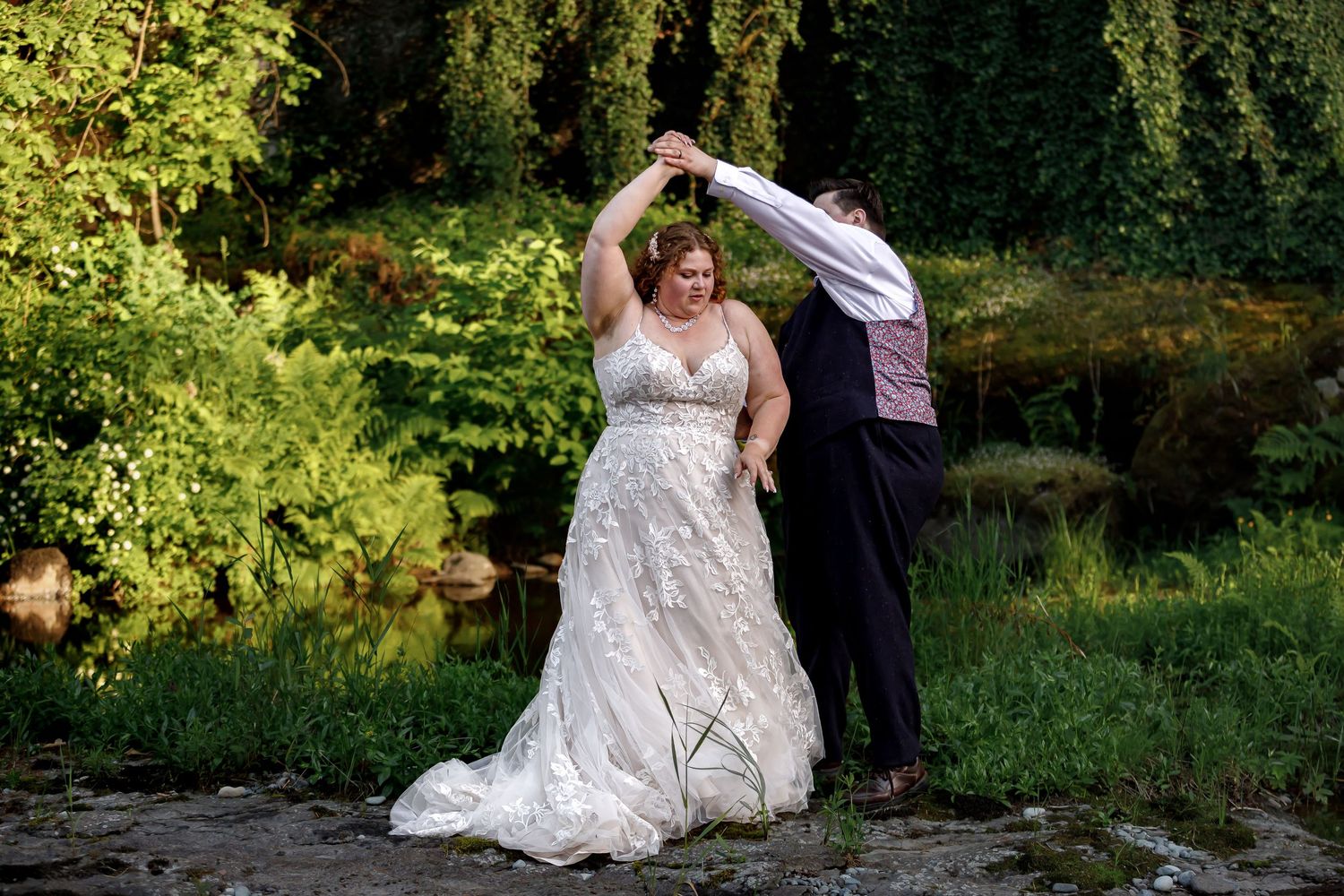 Beautiful golden hour wedding portraits with dramatic poses near a scenic river and greenery.