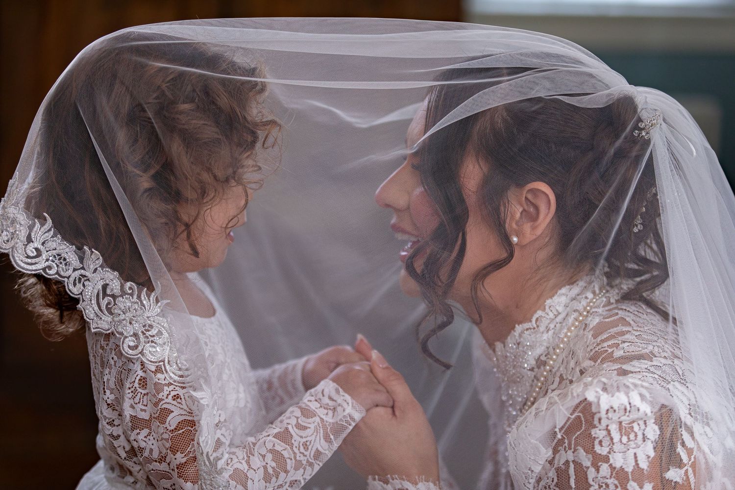 Intimate moment between couple under delicate lace veil.