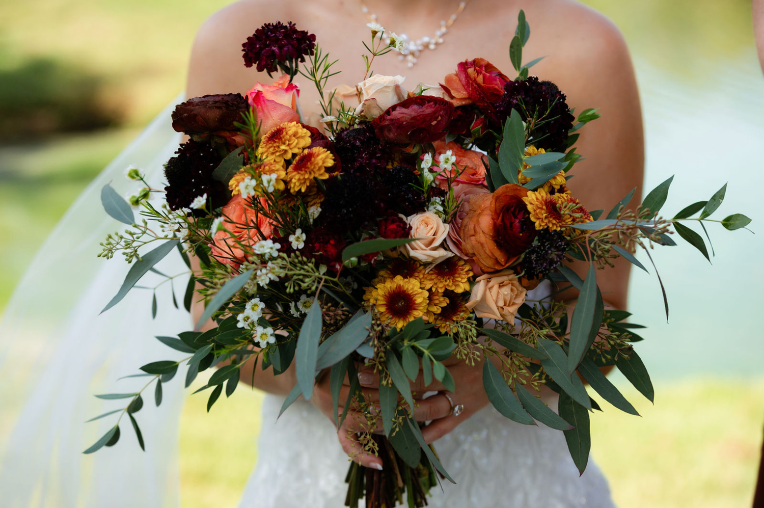 A beautiful floral arrangement with burgundy and orange blooms against a soft background.