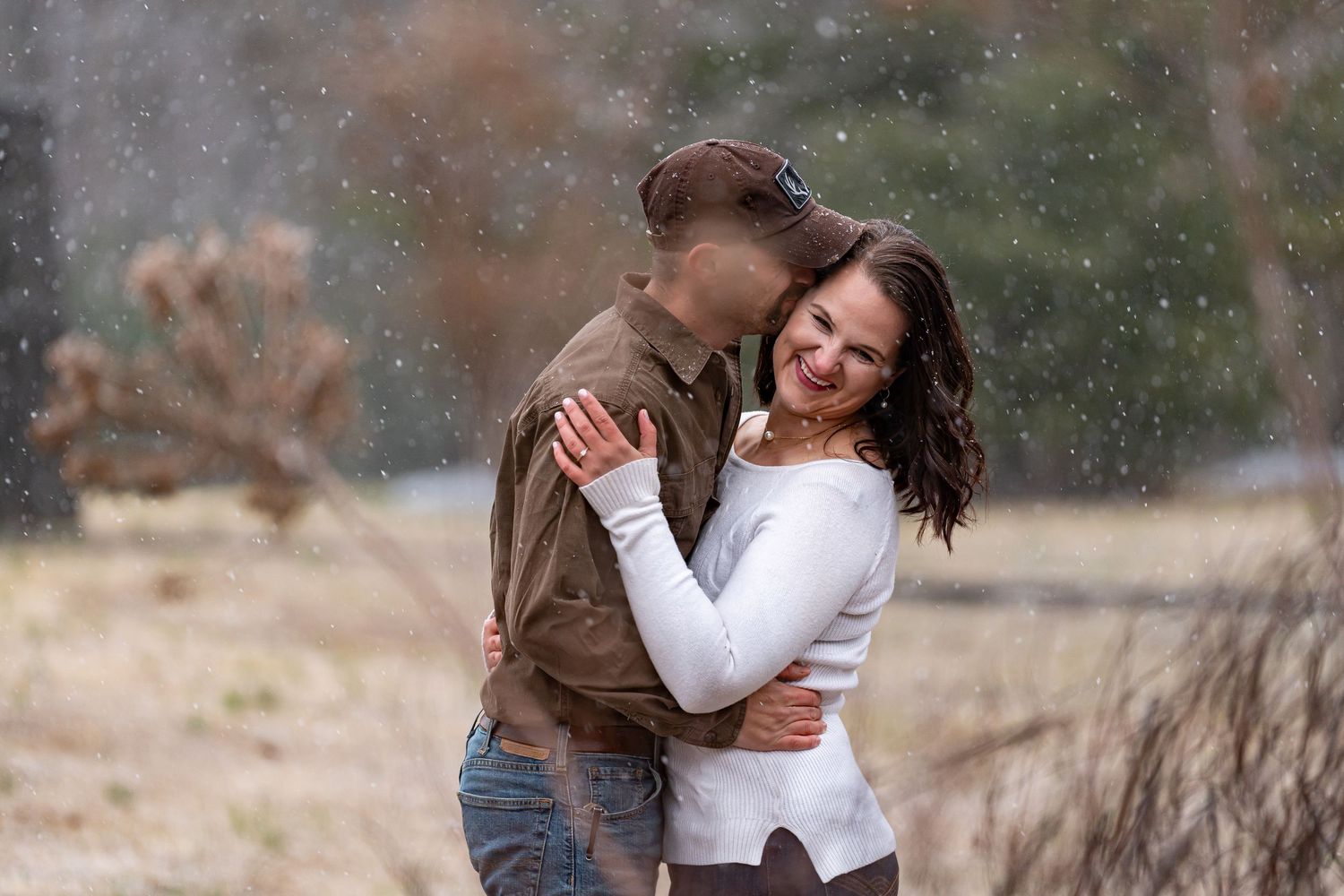 Couple shares intimate moment during light snowfall in winter scene.