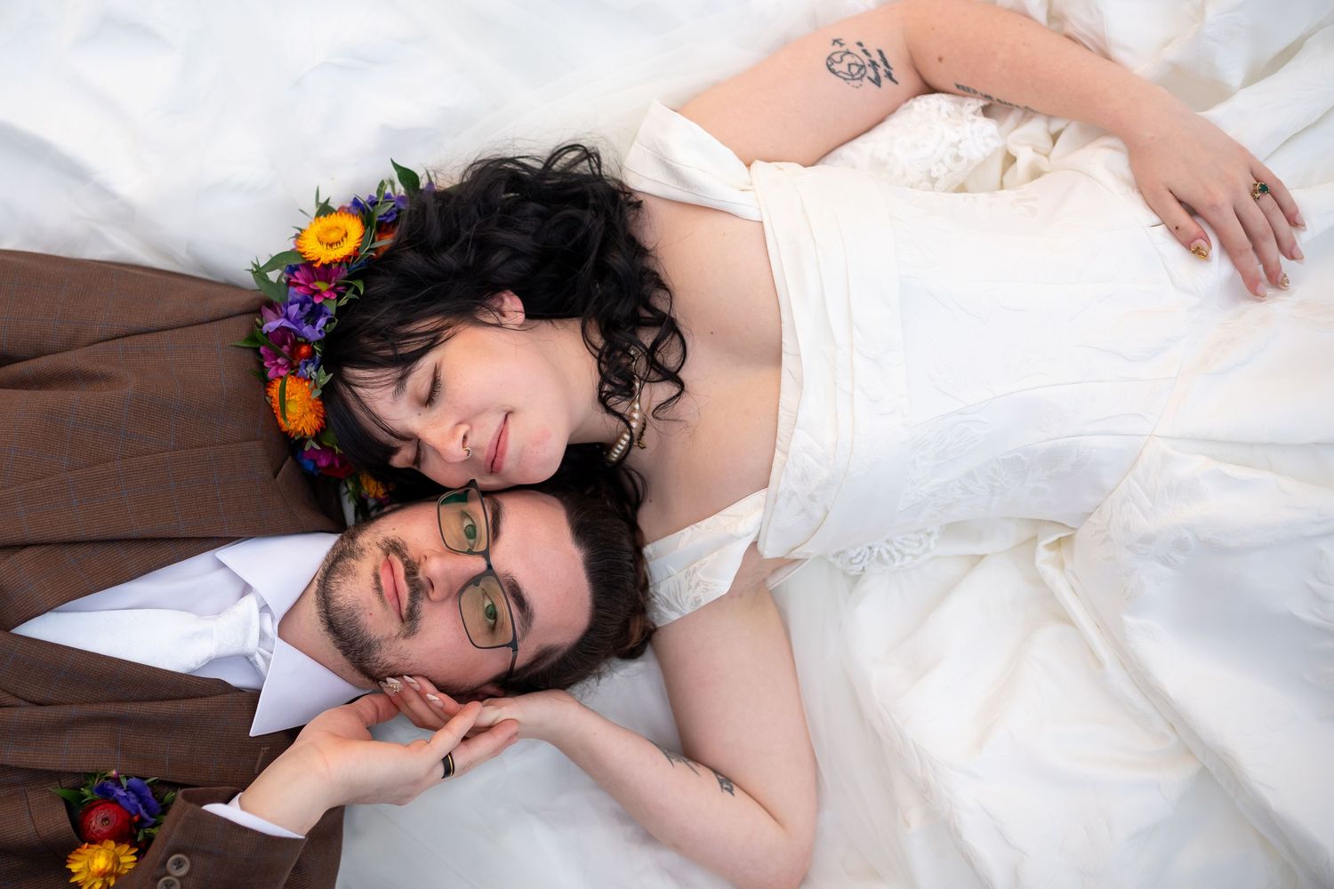White wedding dress flowing across wooden floor with colorful floral accents.
