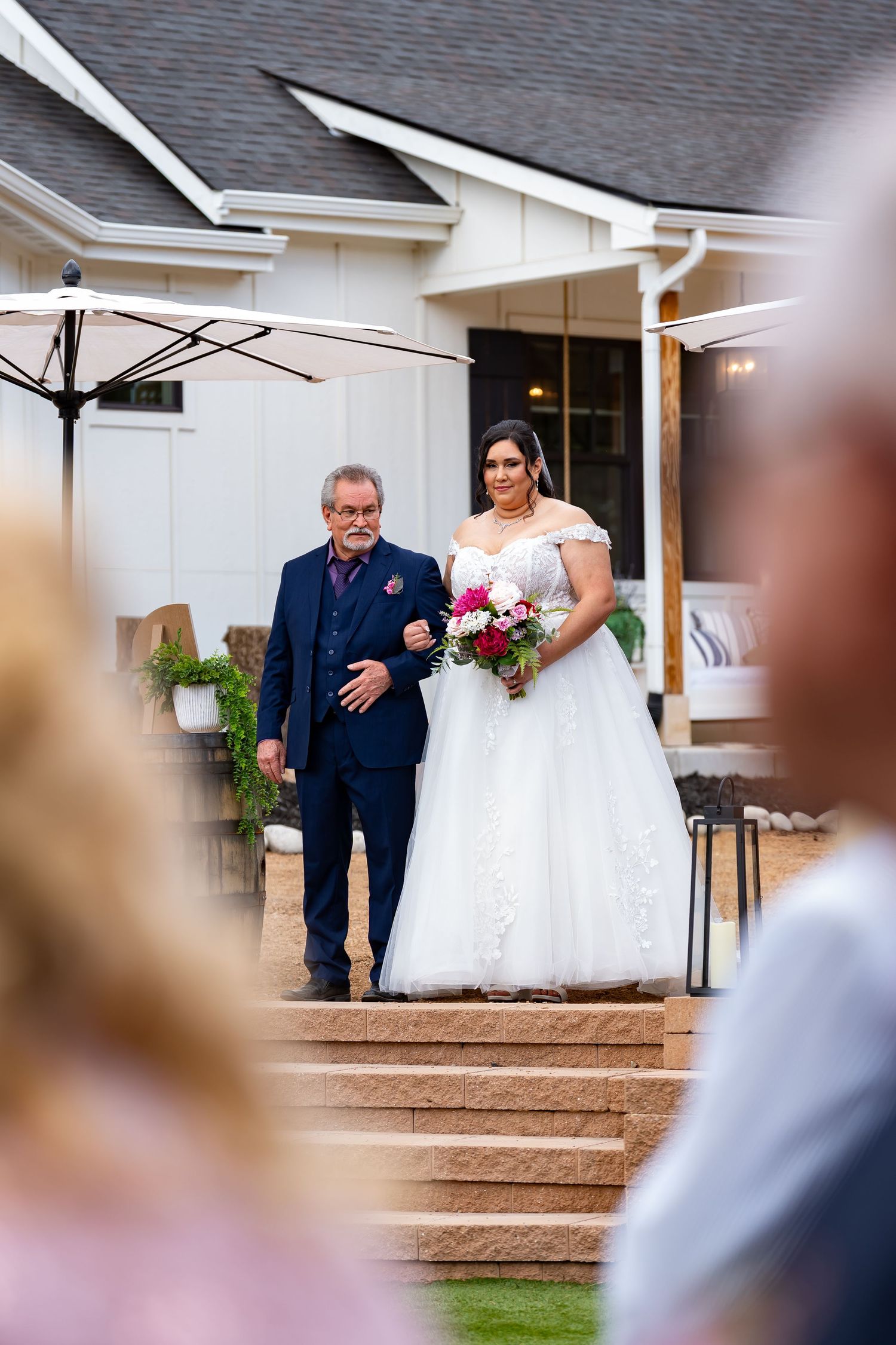 Wedding processional at an outdoor venue with white building backdrop.