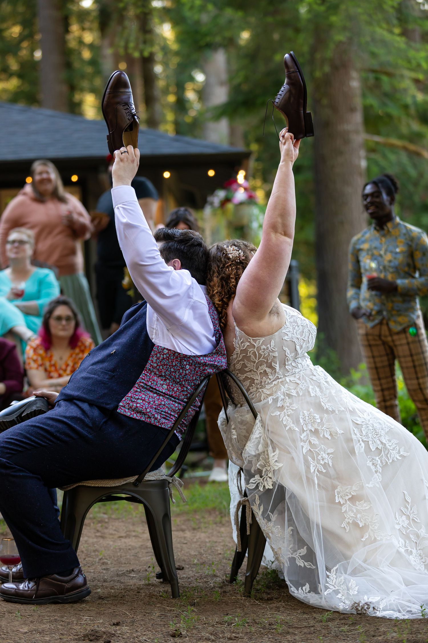 Couple falls backwards dramatically in chairs during outdoor wedding celebration.
