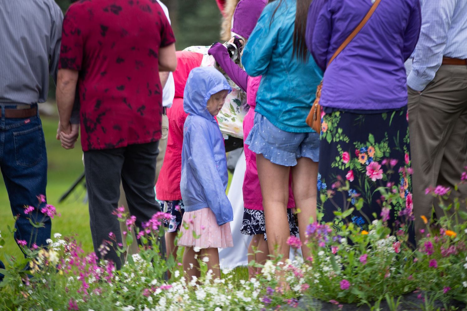 Colorfully dressed wedding guests standing in a flower garden.
