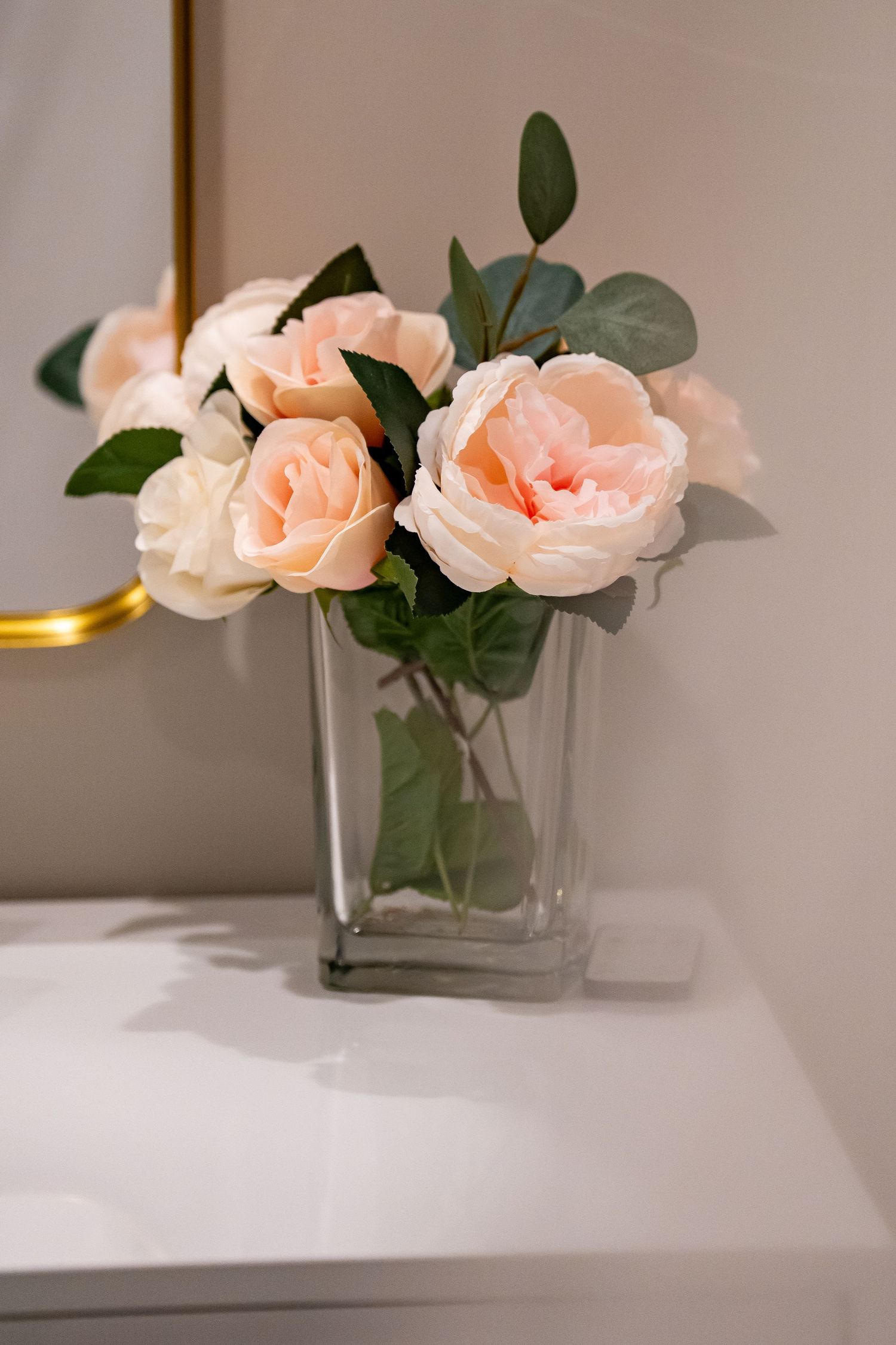 Elegant peach roses arranged in clear glass vases on white surface.
