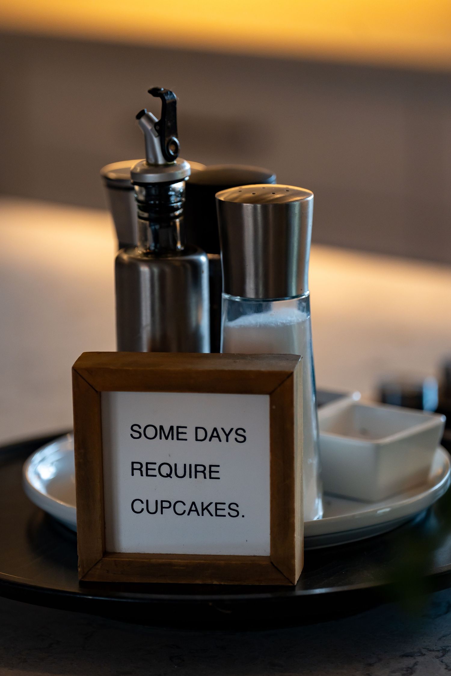 Decorative sign in wooden frame reading 'Some Days Require Cupcakes'.