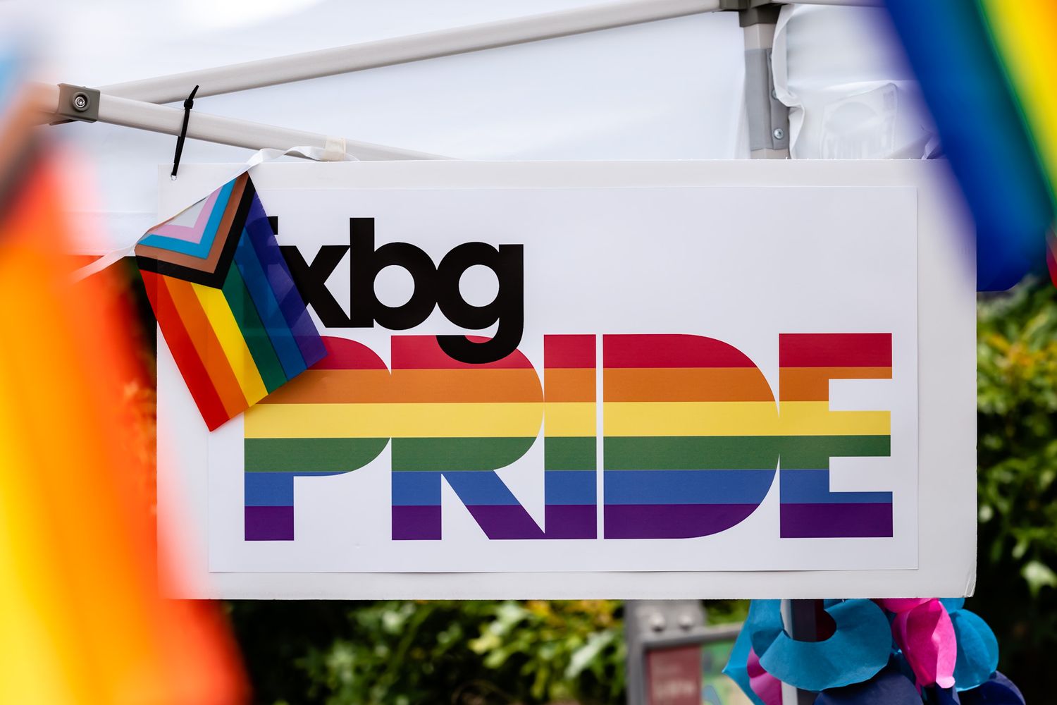 Pride festival signage with rainbow colors and text displayed on white banners.