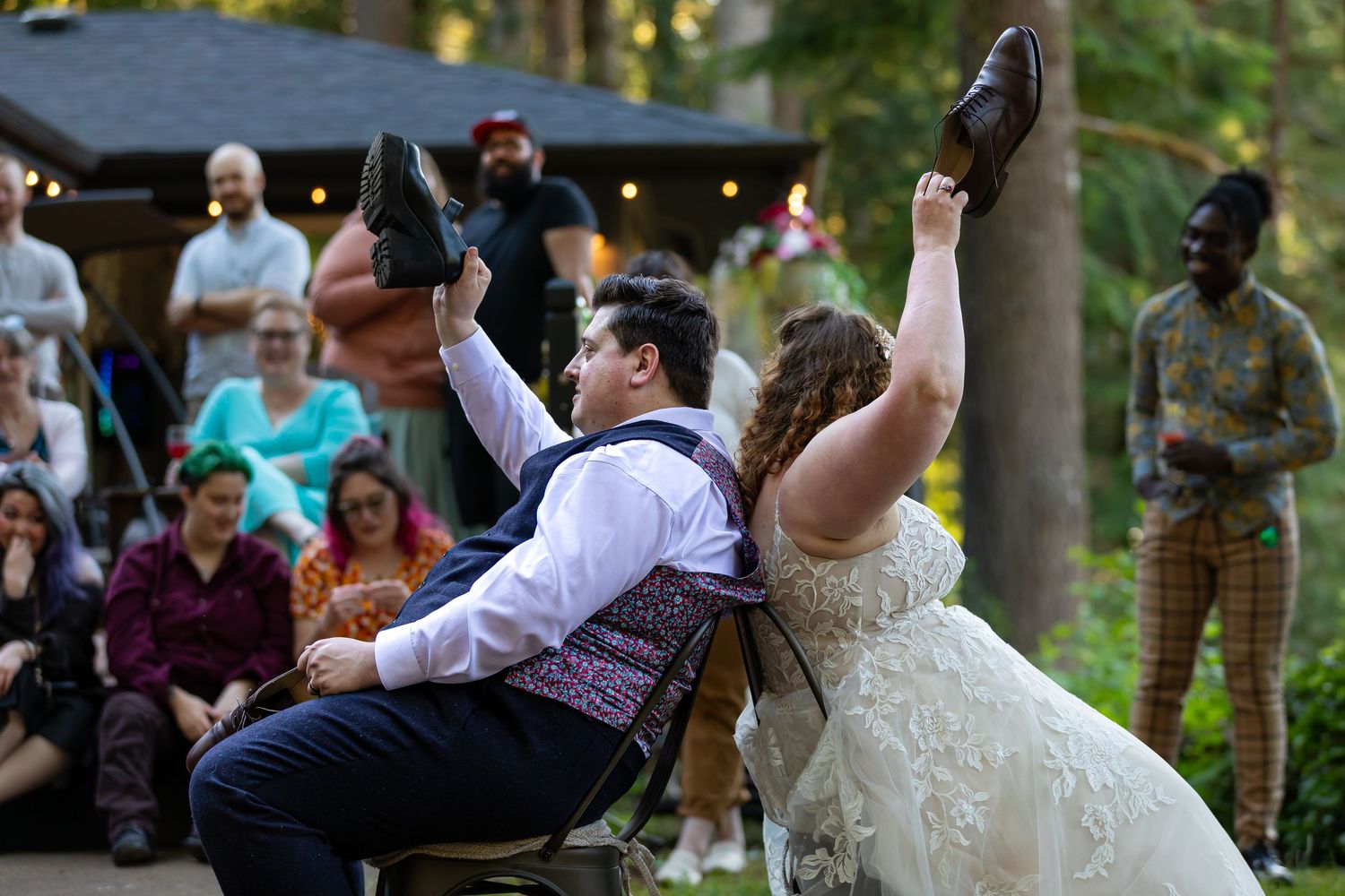 Wedding attendees gather on benches in a sunny outdoor garden setting.