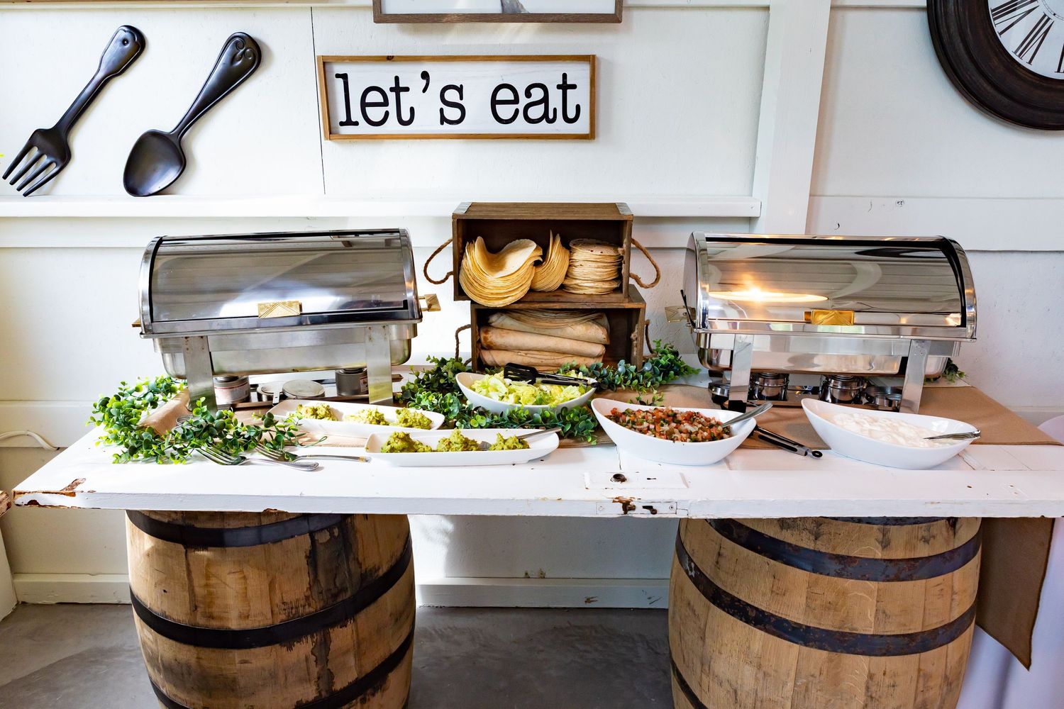 Wedding reception buffet setup with rustic decor and food stations.