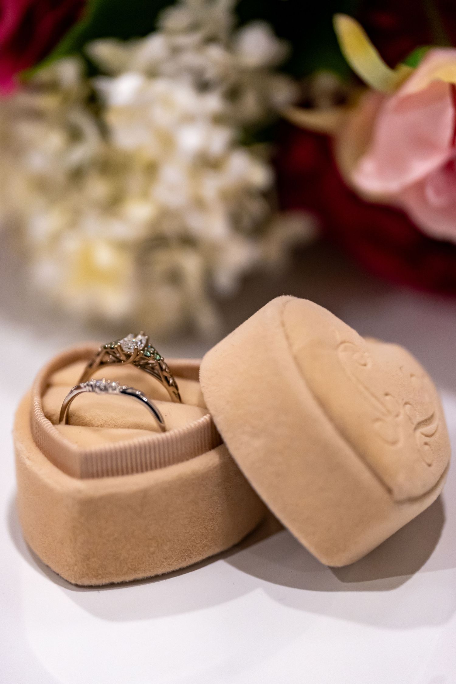 Beige jewelry boxes with wedding rings nestled in soft cushioning.