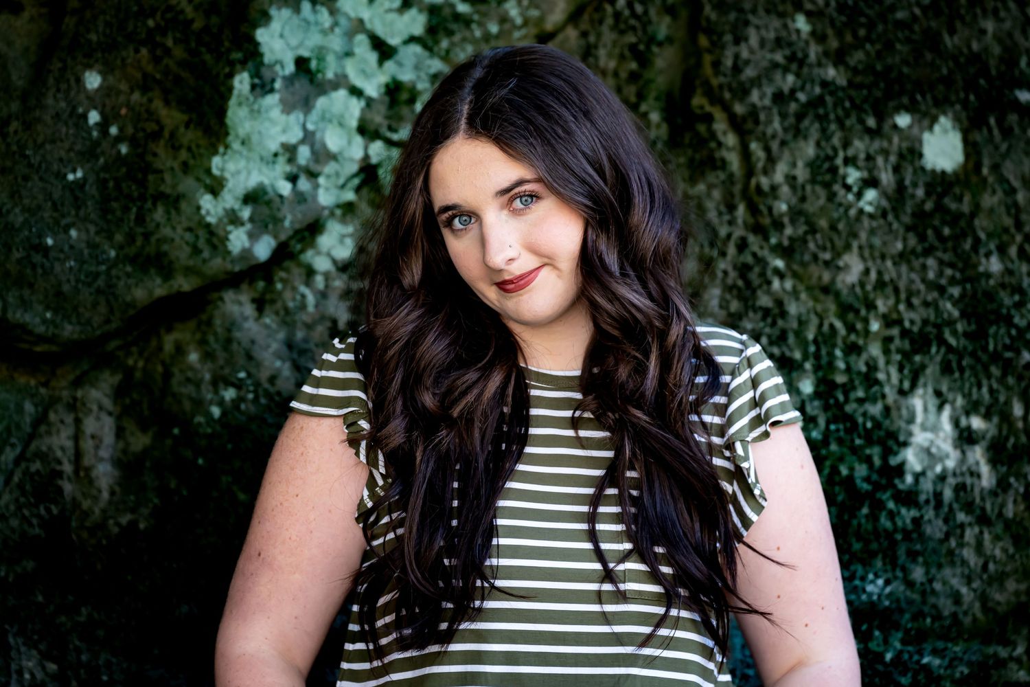 Portrait photo session in a natural outdoor setting with striped top against greenery background.