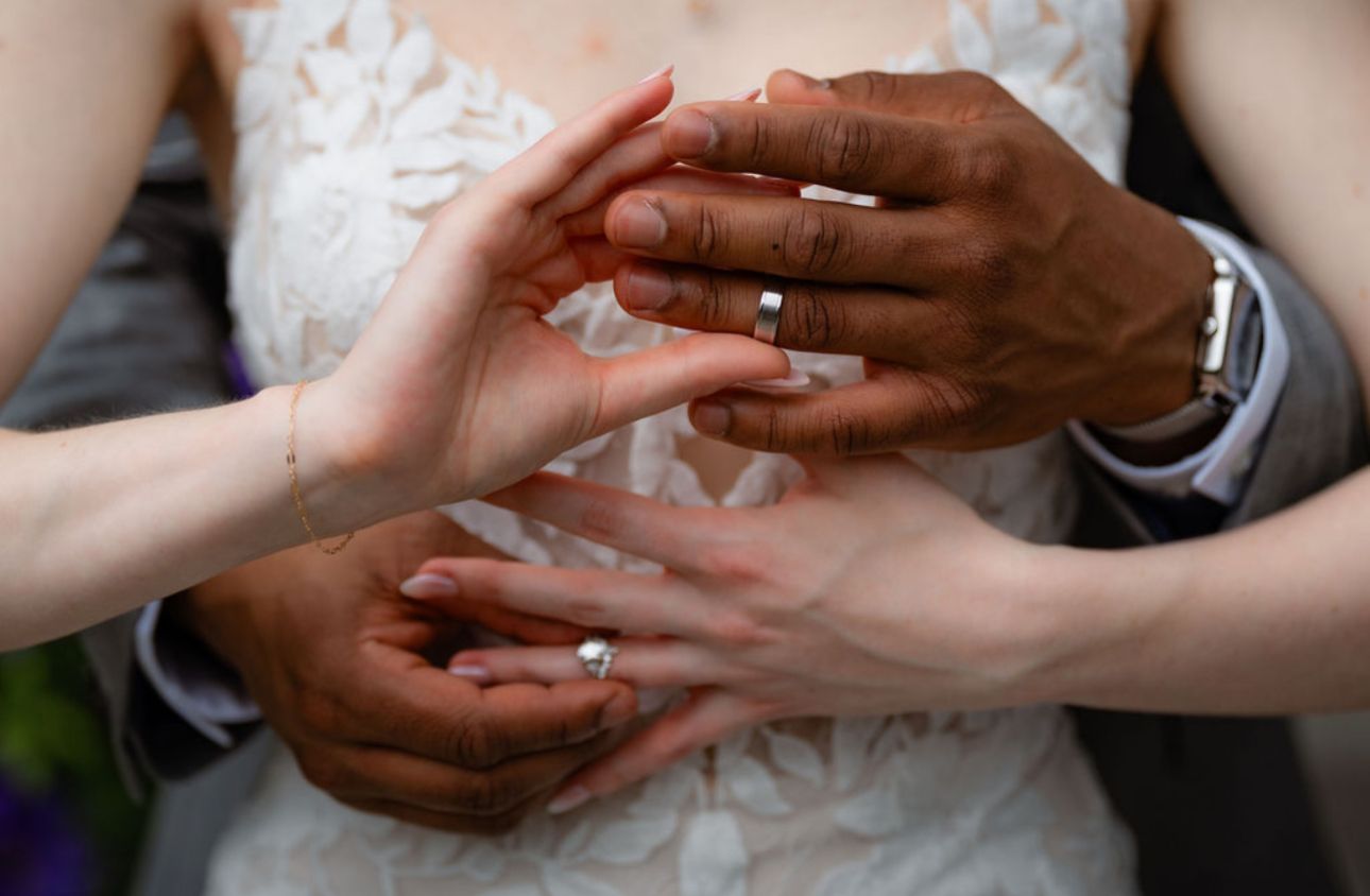 Close-up view of hands exchanging wedding rings during a marriage ceremony.