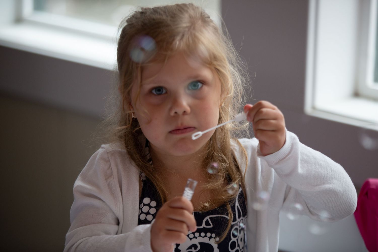 Child in black and white outfit sitting near window during wedding preparations.