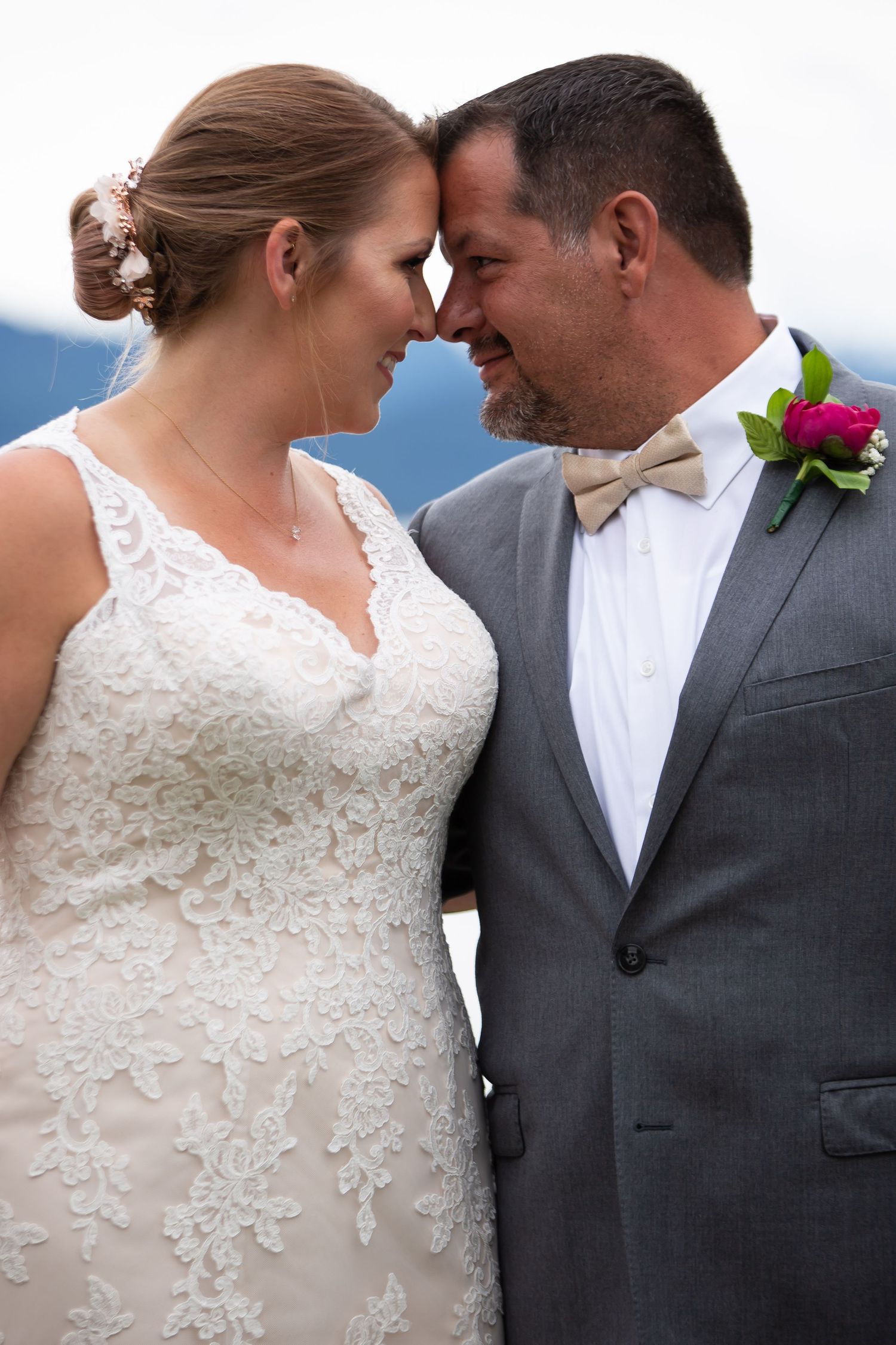 Intimate moment between newlyweds touching foreheads outdoors.