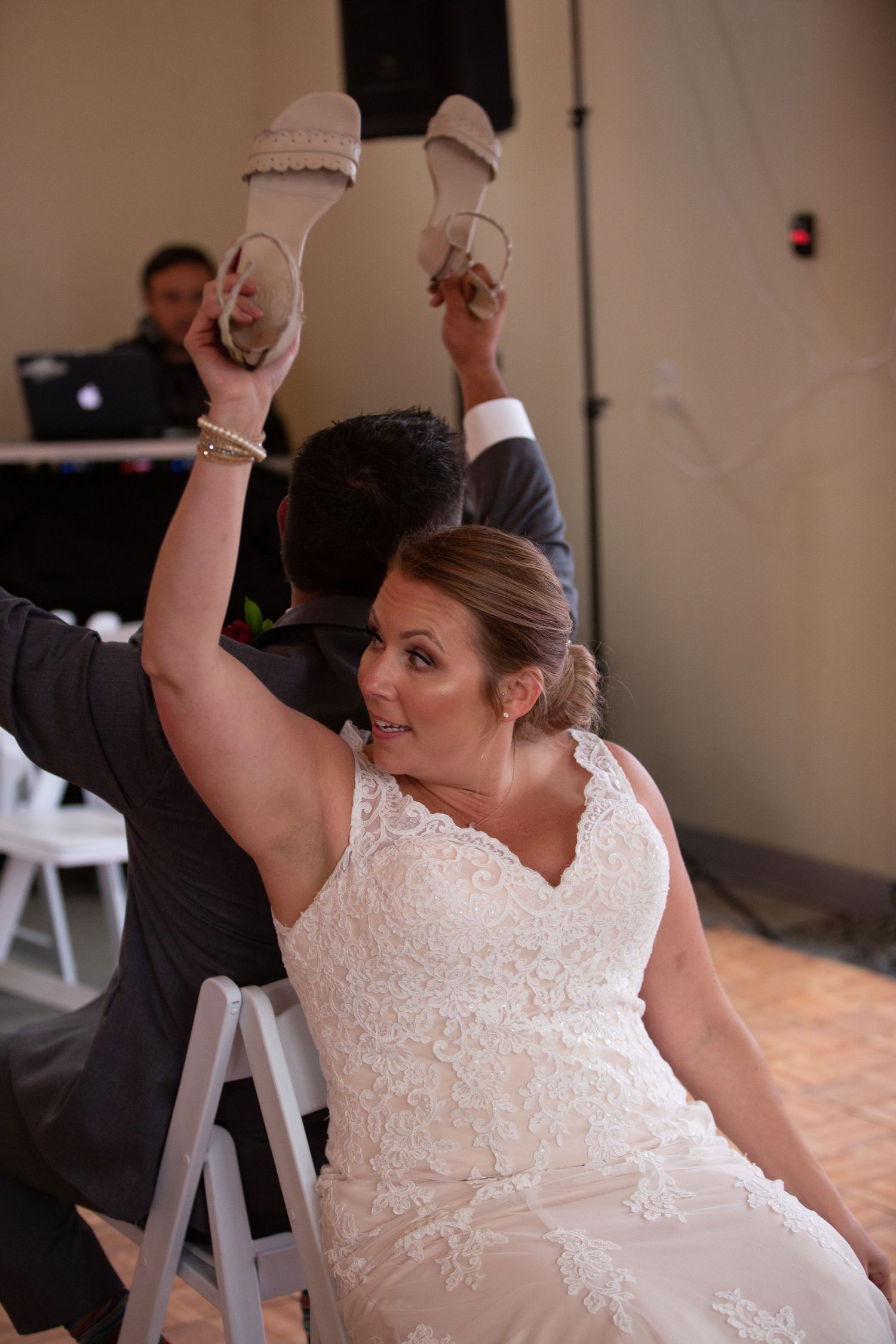 A bride participates in a fun wedding reception game while seated in a chair.