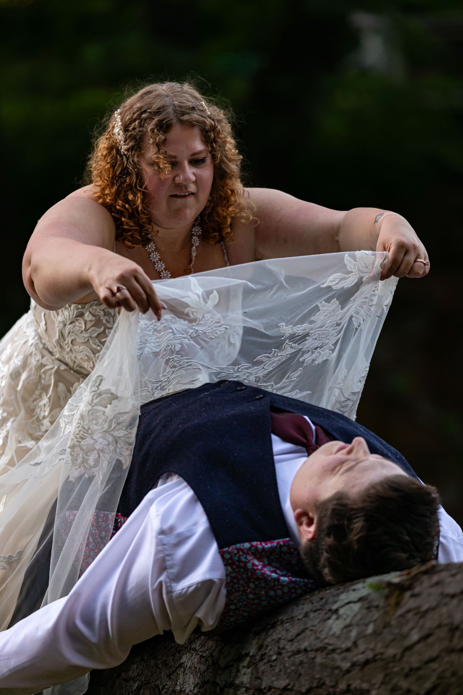 Artistic wedding portrait on rocky surface showcasing lace dress details.