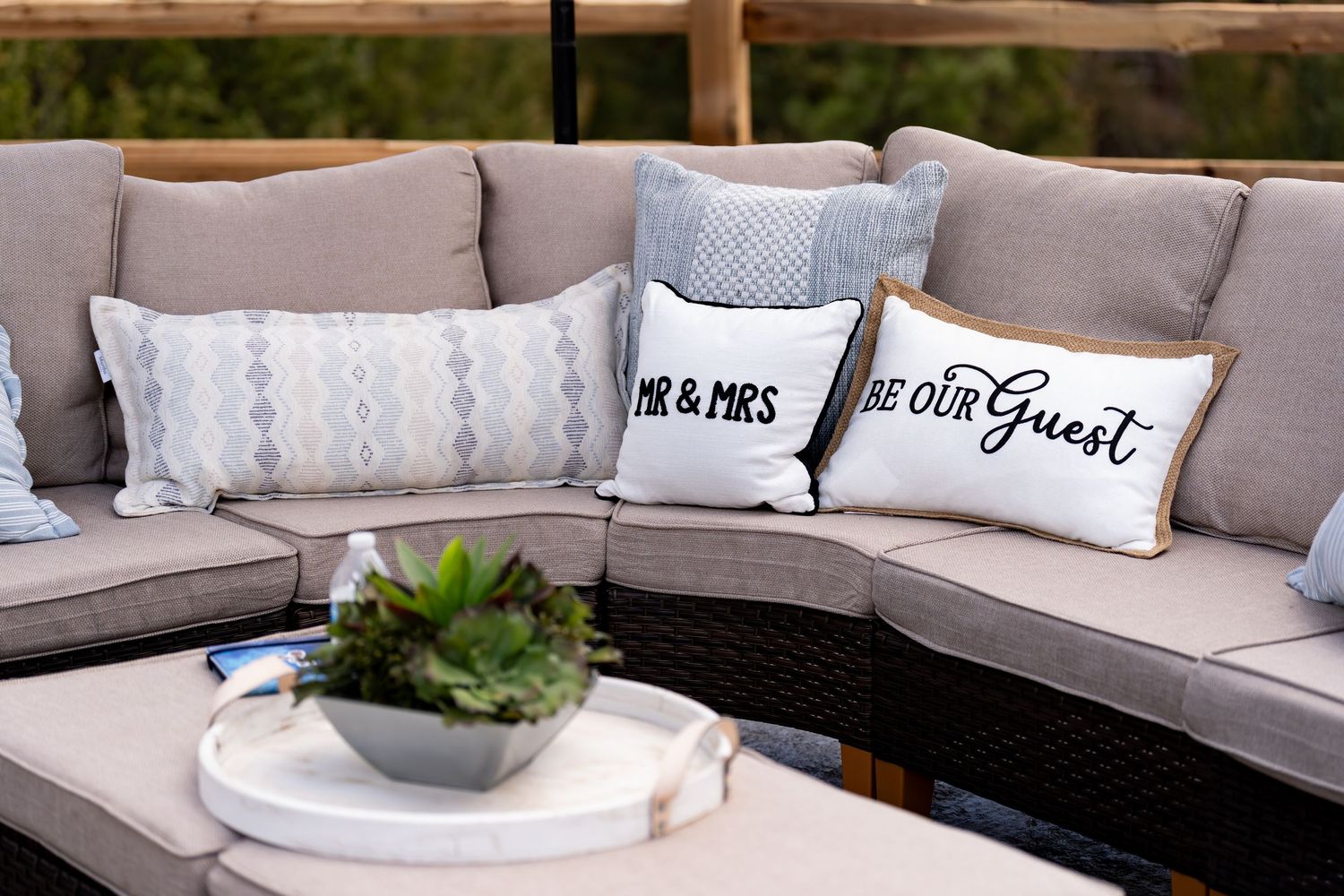 Outdoor sectional sofa with gray cushions and decorative wedding-themed throw pillows.