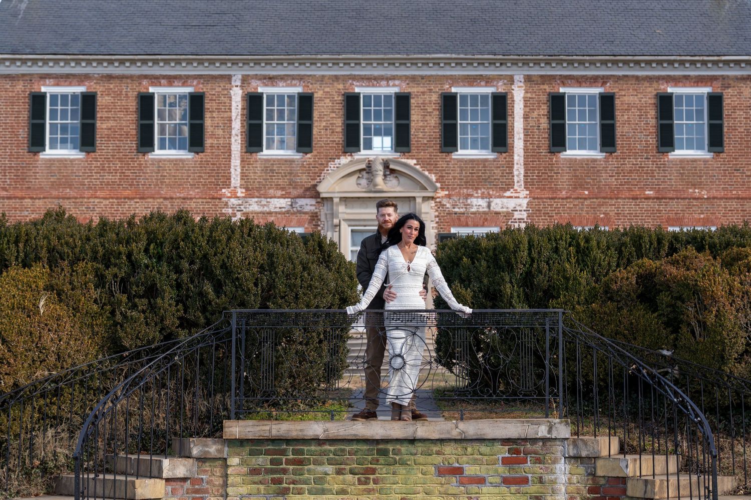 A historic brick building with white trim and multiple symmetrical windows creates an elegant backdrop.