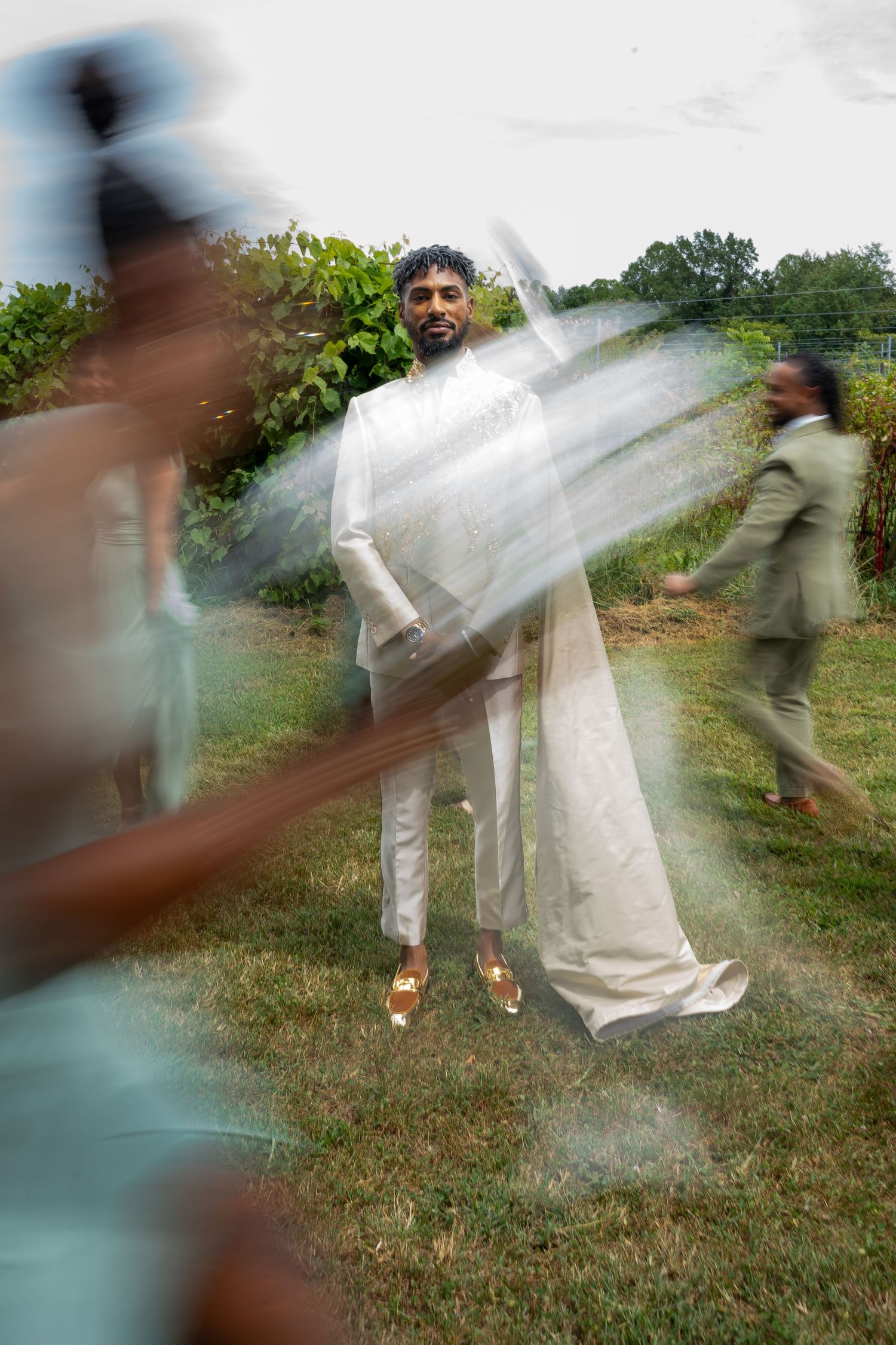 Artistic motion blur photography of figures in white moving across a grassy field.