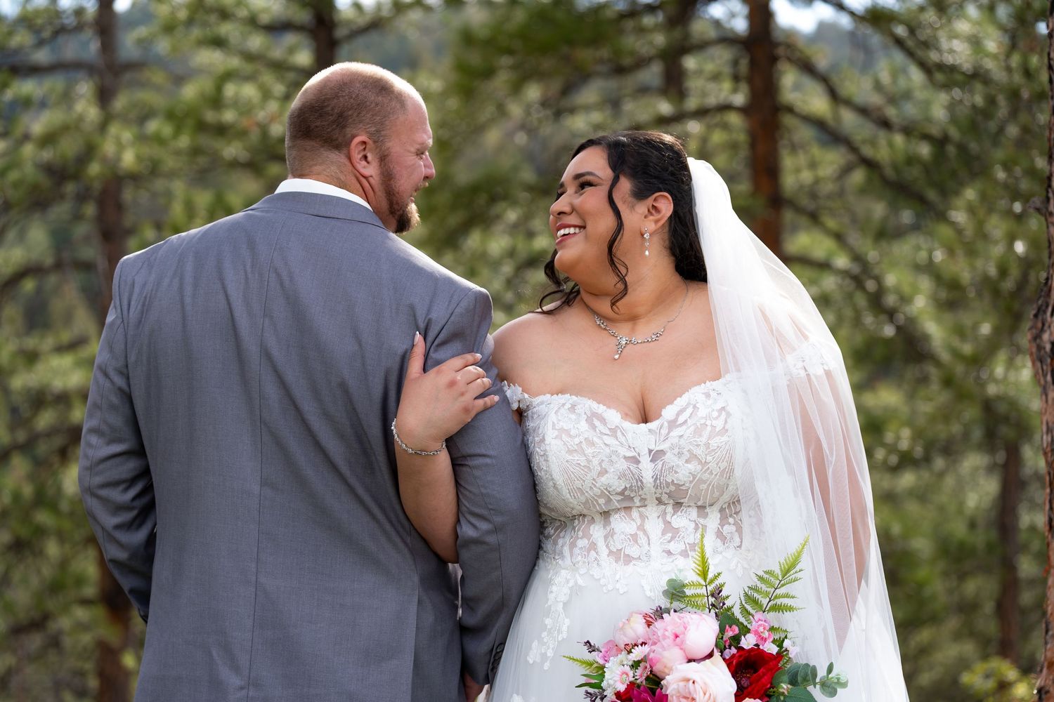 Intimate wedding couple portraits captured outdoors among towering pine trees.