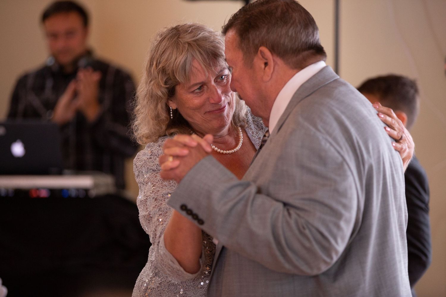 Couple sharing a romantic dance at wedding reception with piano in background.