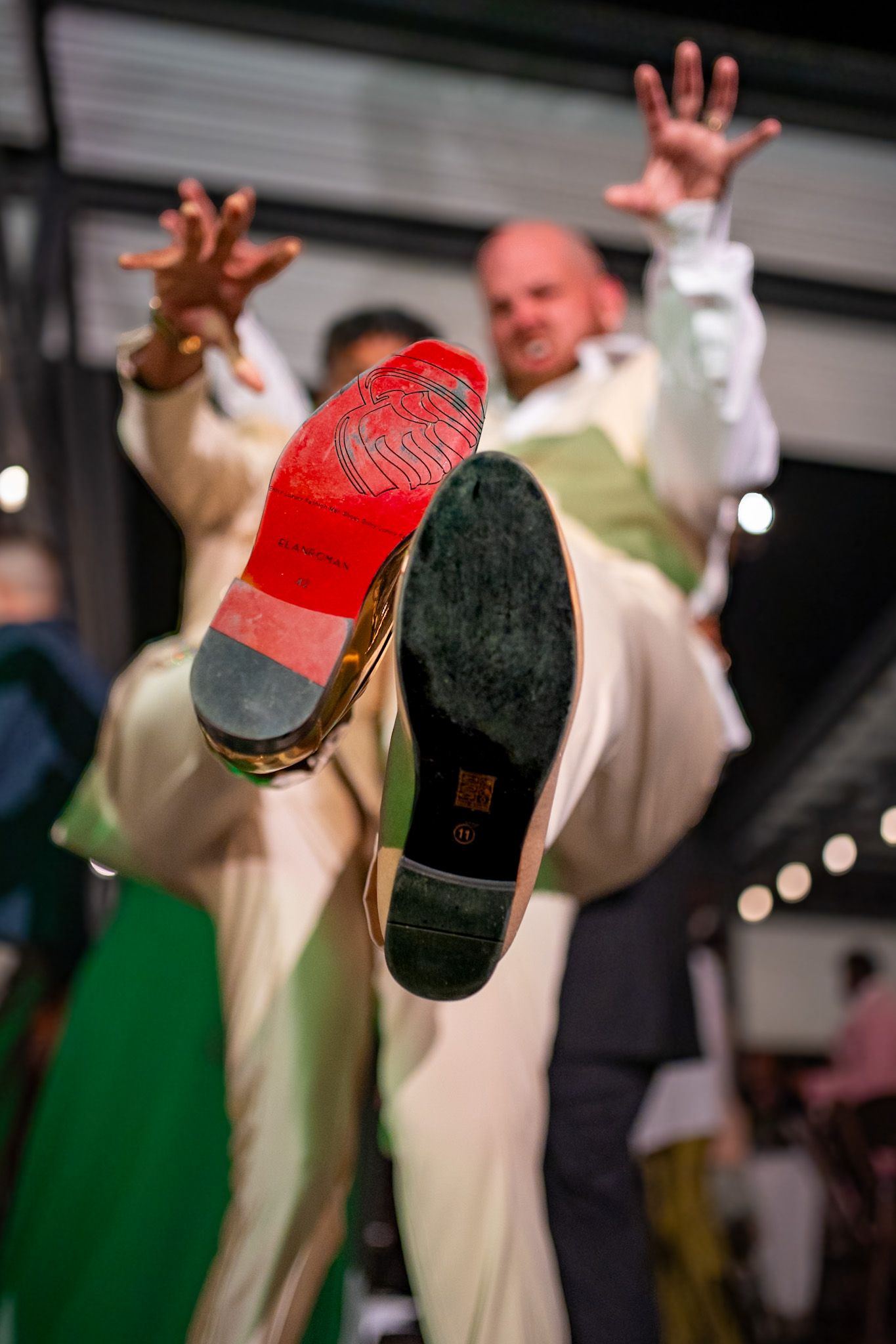Creative photo showing bottom of shoes raised in the air during a wedding celebration.