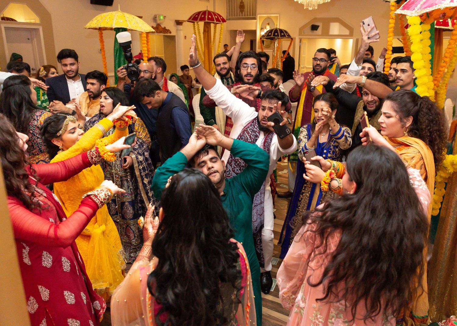 Energetic wedding celebration with guests dancing in colorful traditional Indian attire.