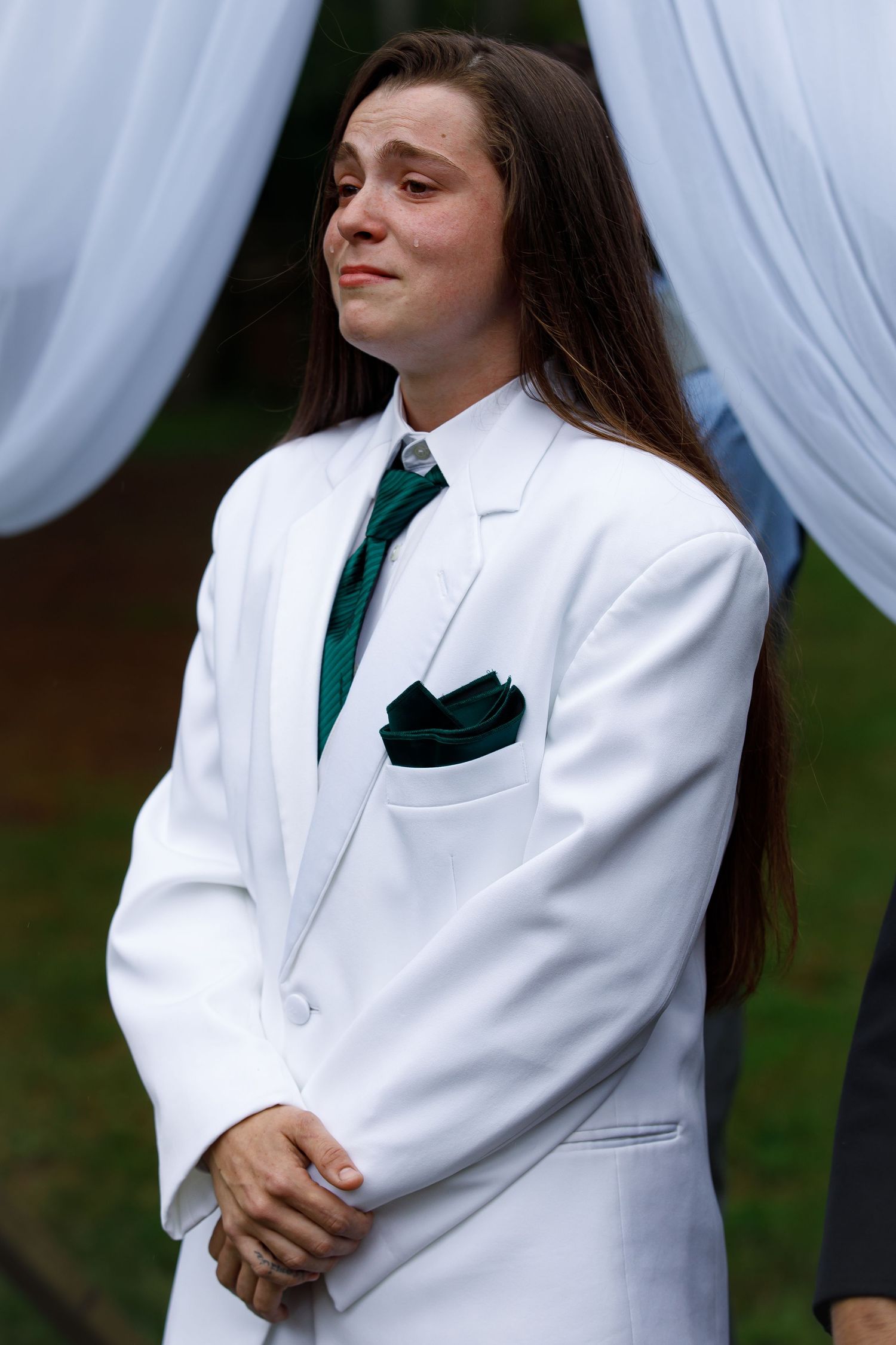 Wedding attire featuring a crisp white suit with emerald green tie and pocket square.