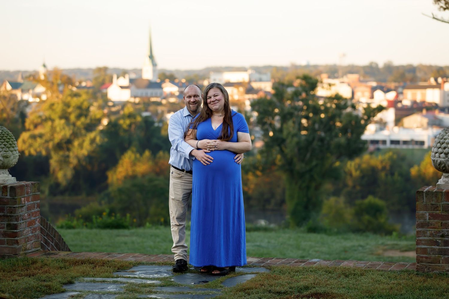 Couple poses at sunset in front of a historic brick building with stone steps.