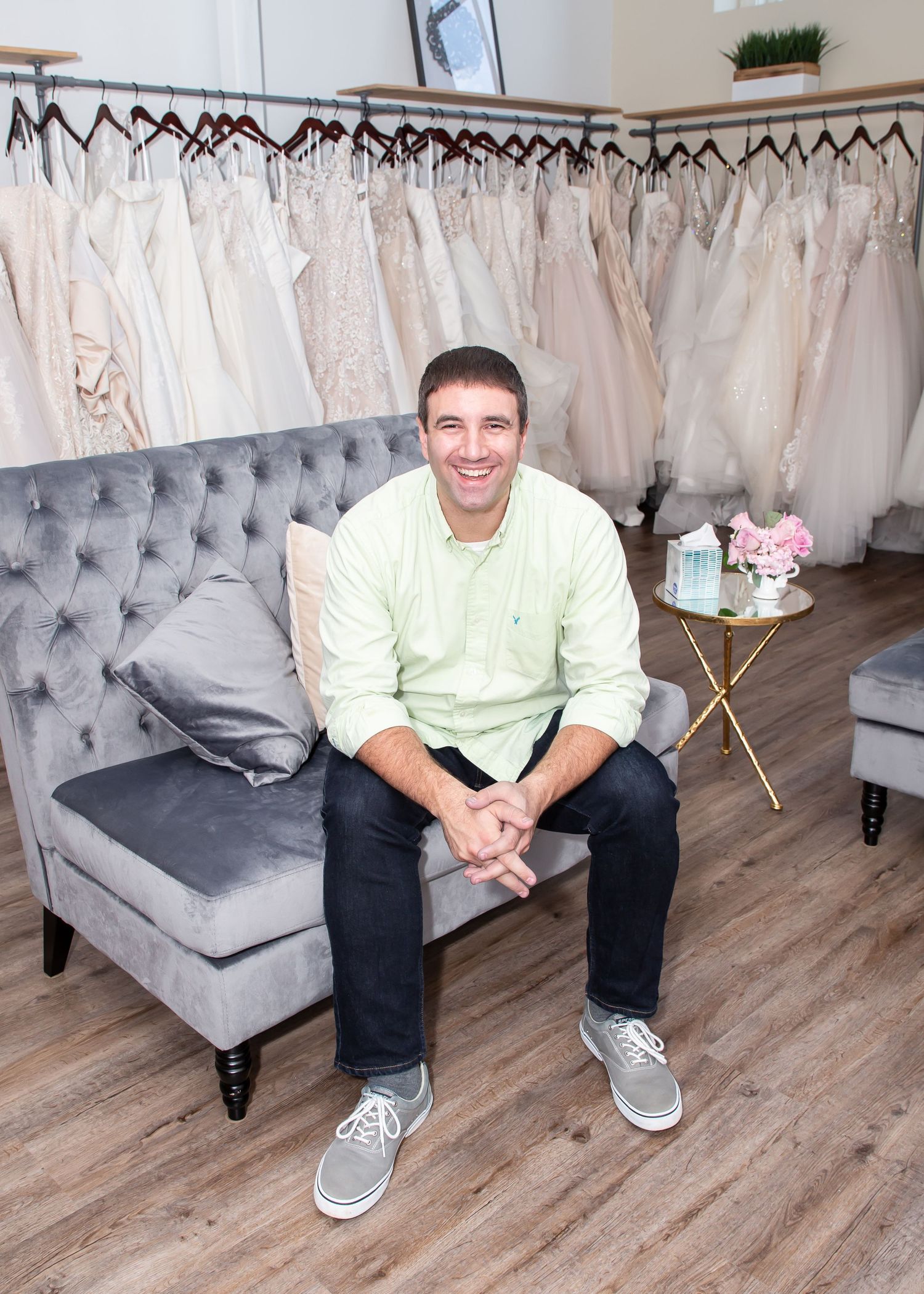 Modern bridal shop interior featuring gray tufted bench and hardwood flooring.
