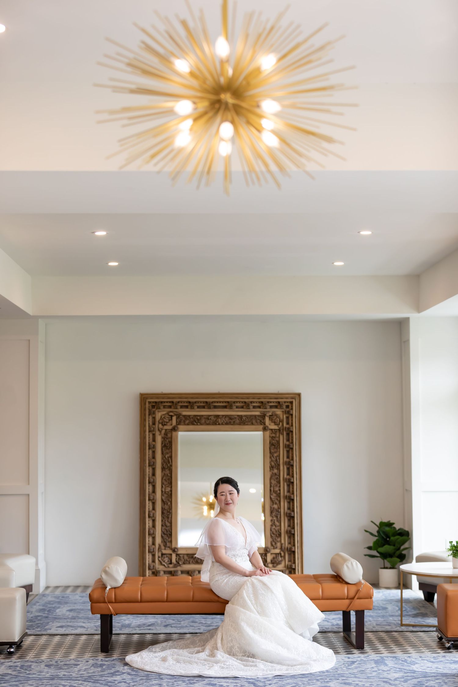 Elegant interior room sequence showing a sunburst chandelier and decorative mirror with white paneled walls.
