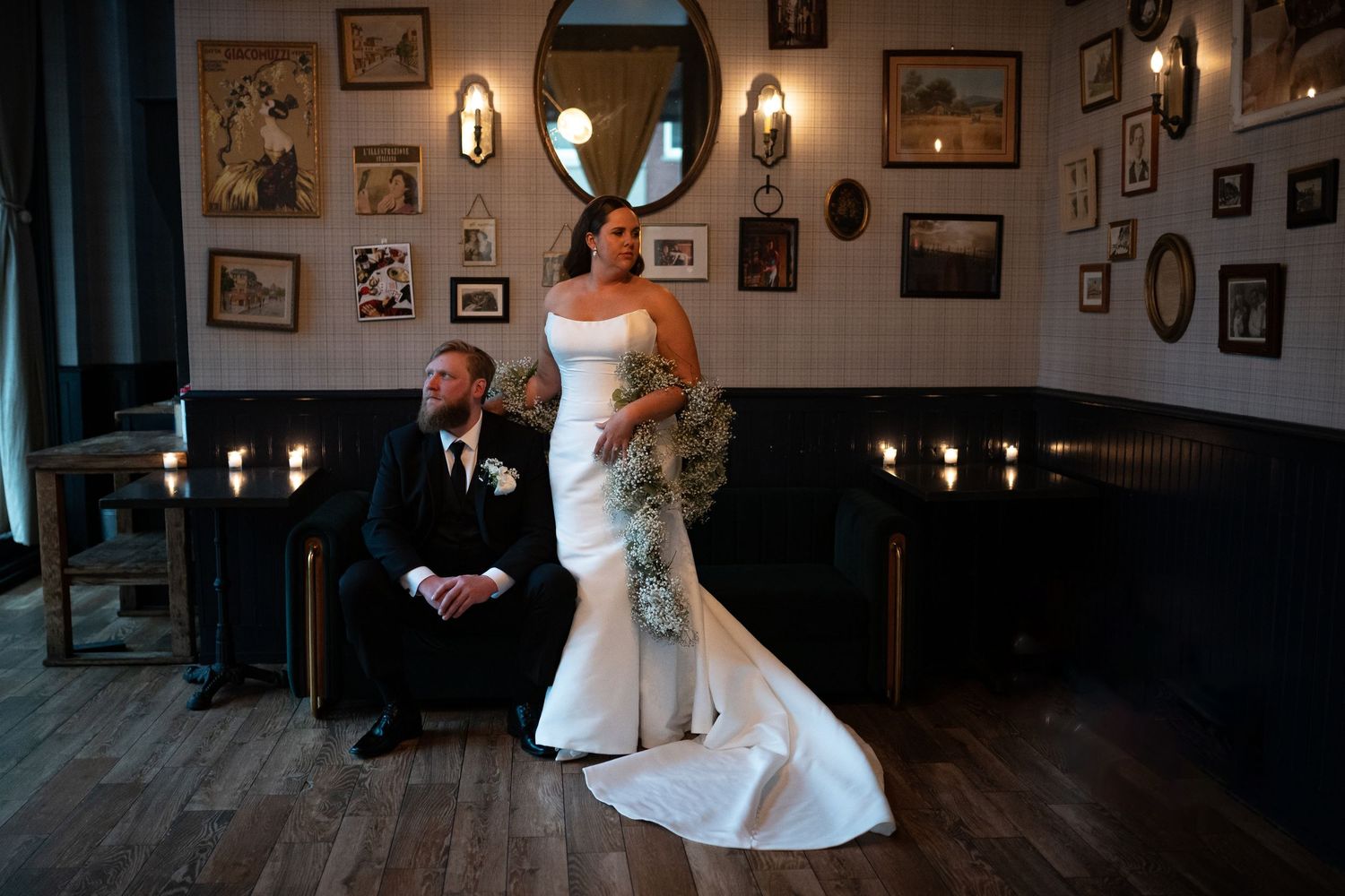 Wedding celebration in a dimly lit vintage room with framed photos on walls.