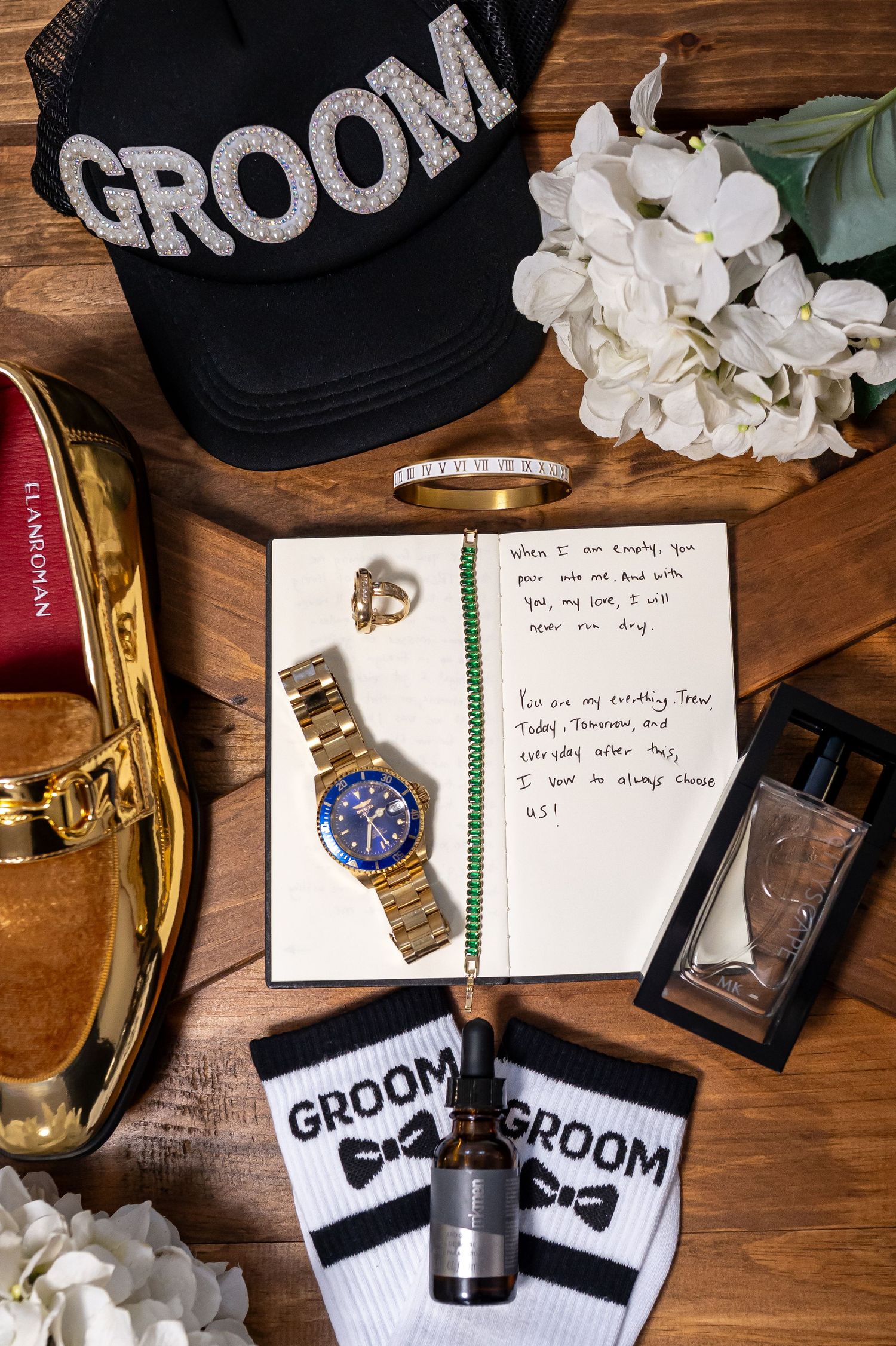 Wedding details including groom socks, handwritten notes, and white floral arrangements on wooden surface.