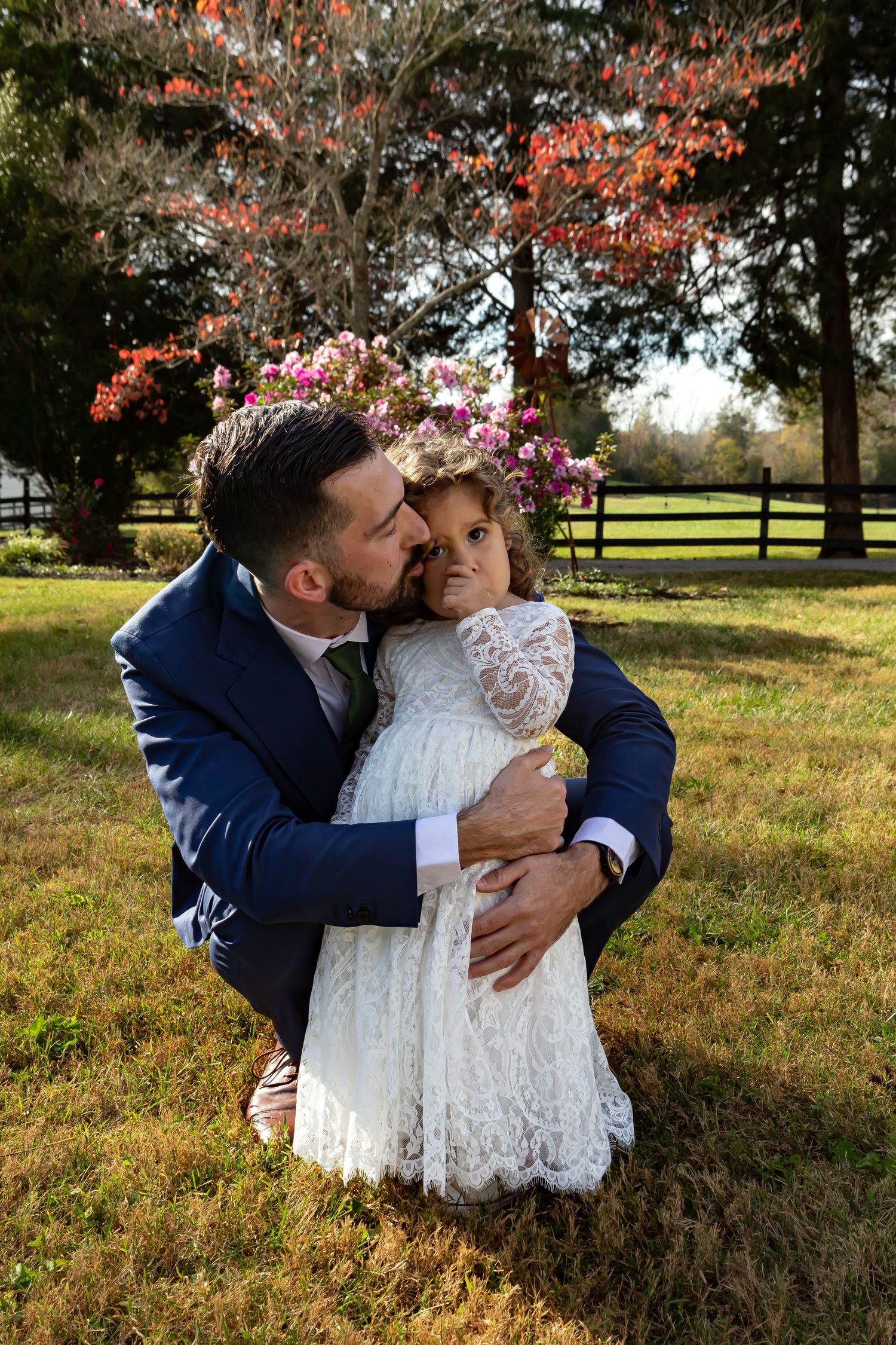 Sweet moment between parent and child in formal attire among autumn trees.