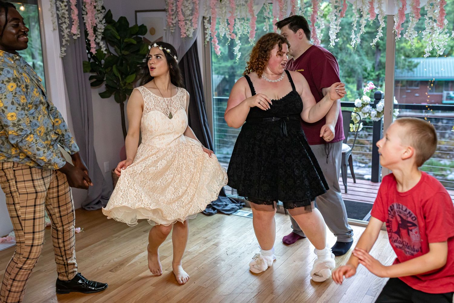Wedding party dancing and celebrating on a wooden dance floor with festive decorations.