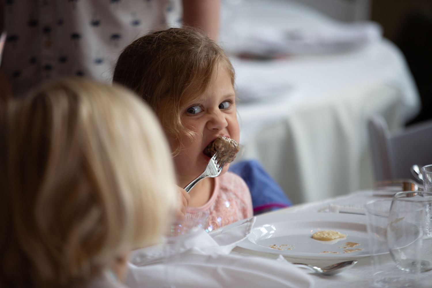 Young child enjoys a meal at an elegant table setting during a reception.