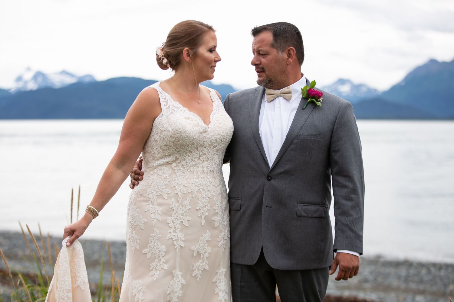 Wedding couple posing together with mountain lake backdrop.