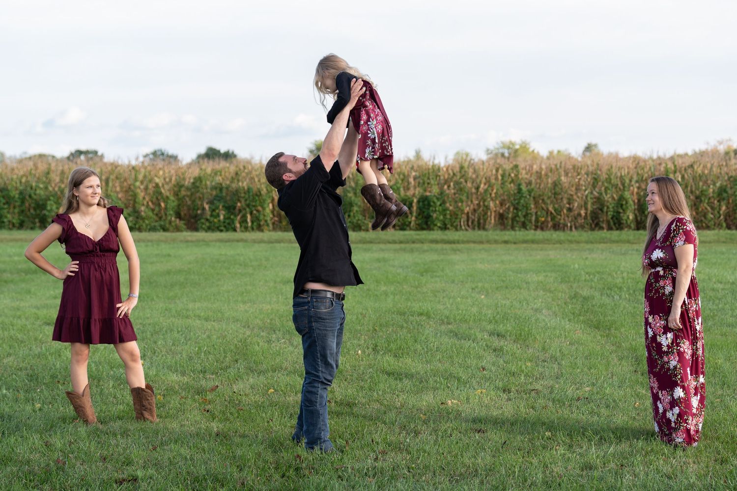 Playful outdoor photography session in a grassy field on a sunny day.