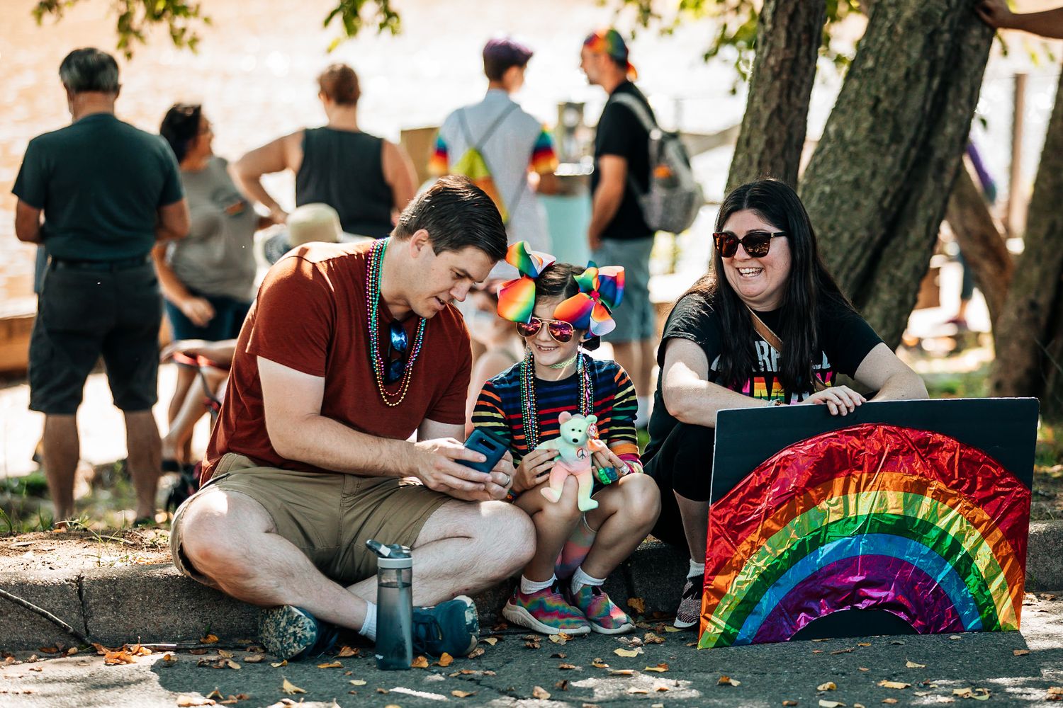 People relaxing on grass at outdoor pride festival with rainbow decorations.