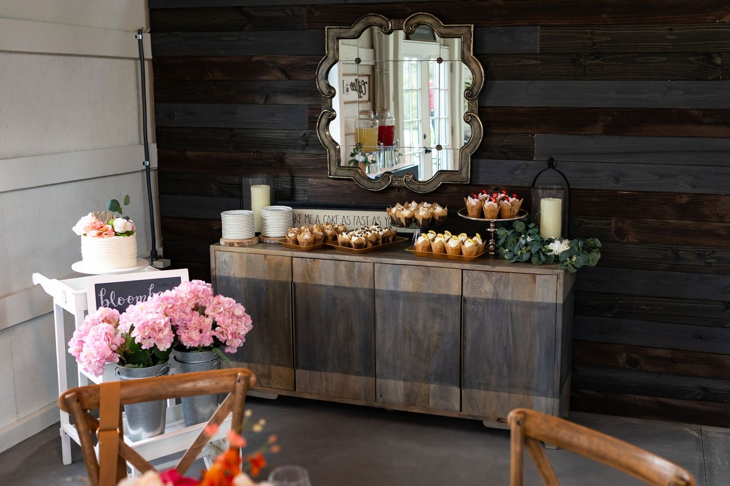 Rustic wooden tables and chairs arranged in a barn venue with natural light streaming through windows.