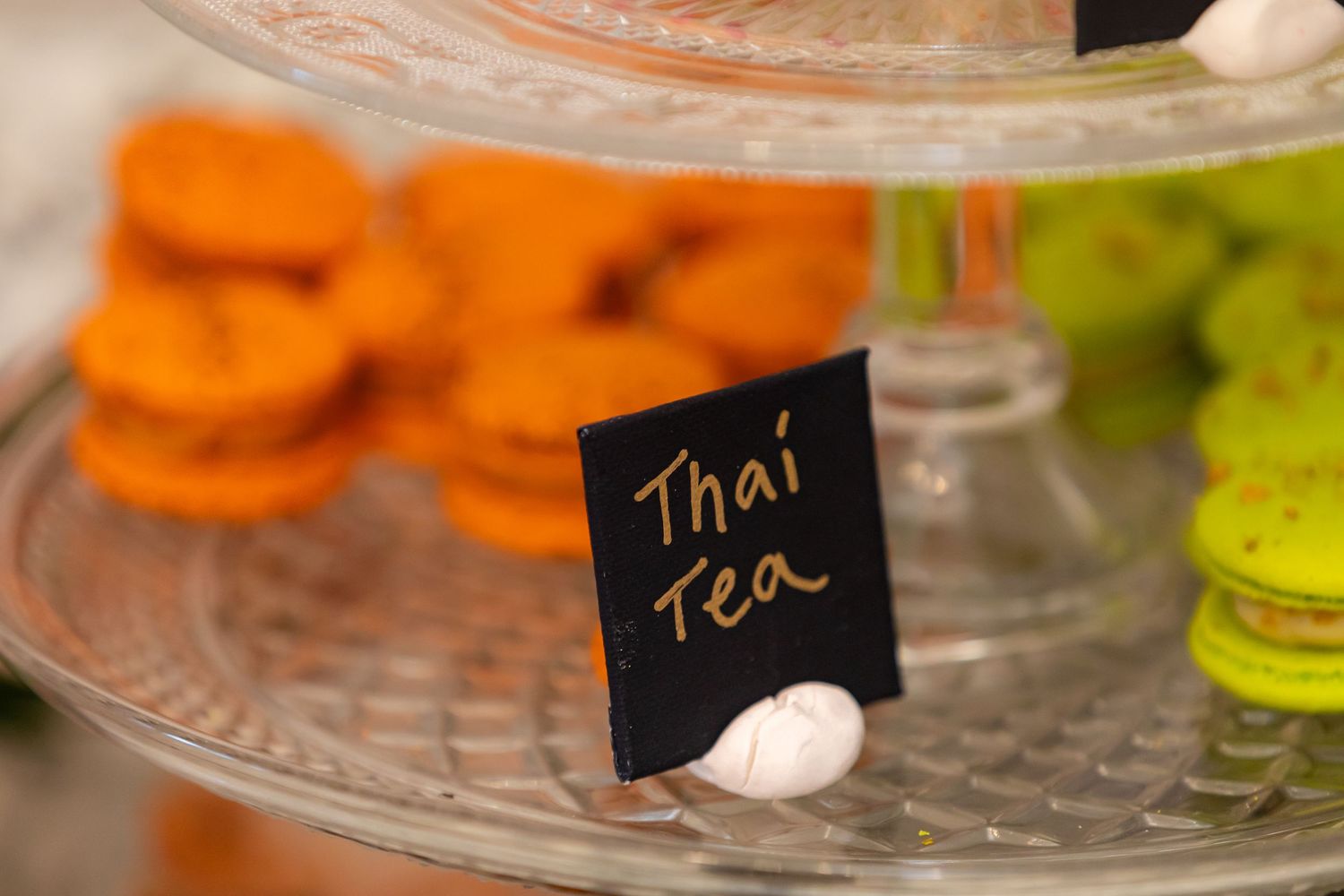 Glass display stands presenting an assortment of pastel-colored French macarons with small label markers.