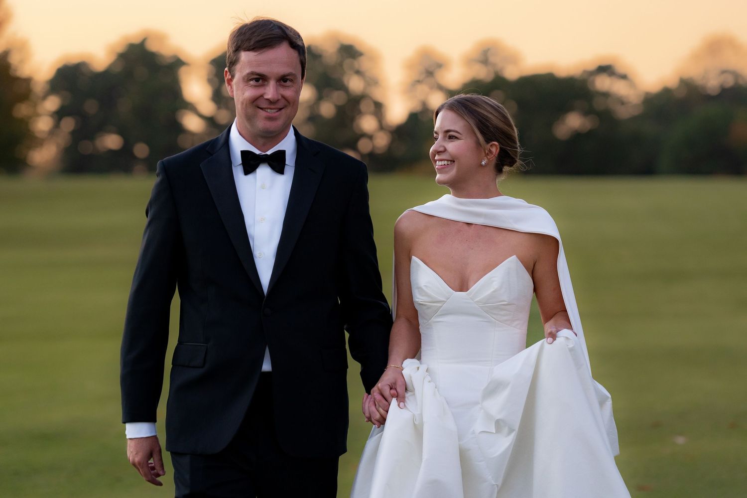 A couple shares intimate moments on a sunny golf course in formal wedding attire.