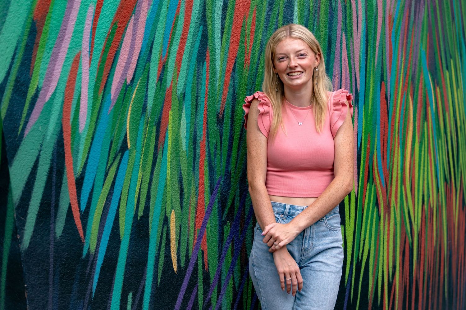 Vibrant green and pink striped wall creates artistic backdrop for portrait.