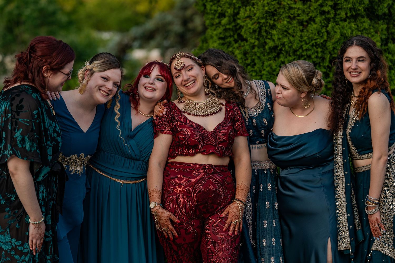 Bridesmaids in elegant blue and burgundy dresses share a joyful moment together.