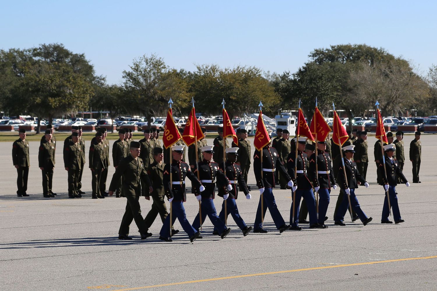 Military color guard unit marching in ceremonial formation with flags.