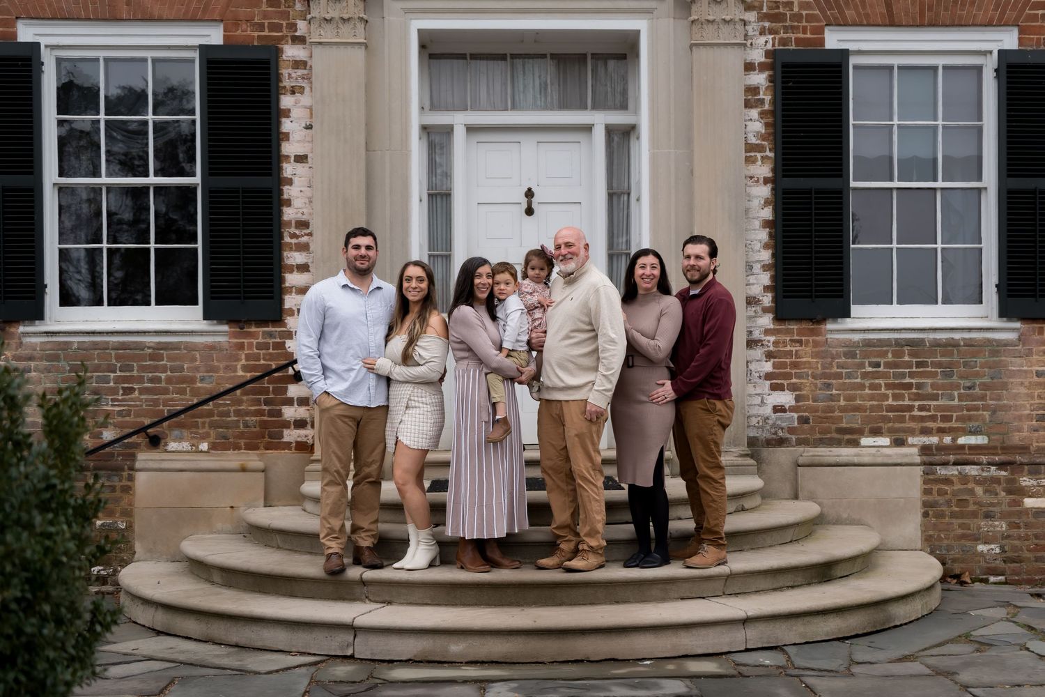 Group photo of extended family gathered on stone steps of historic brick building.