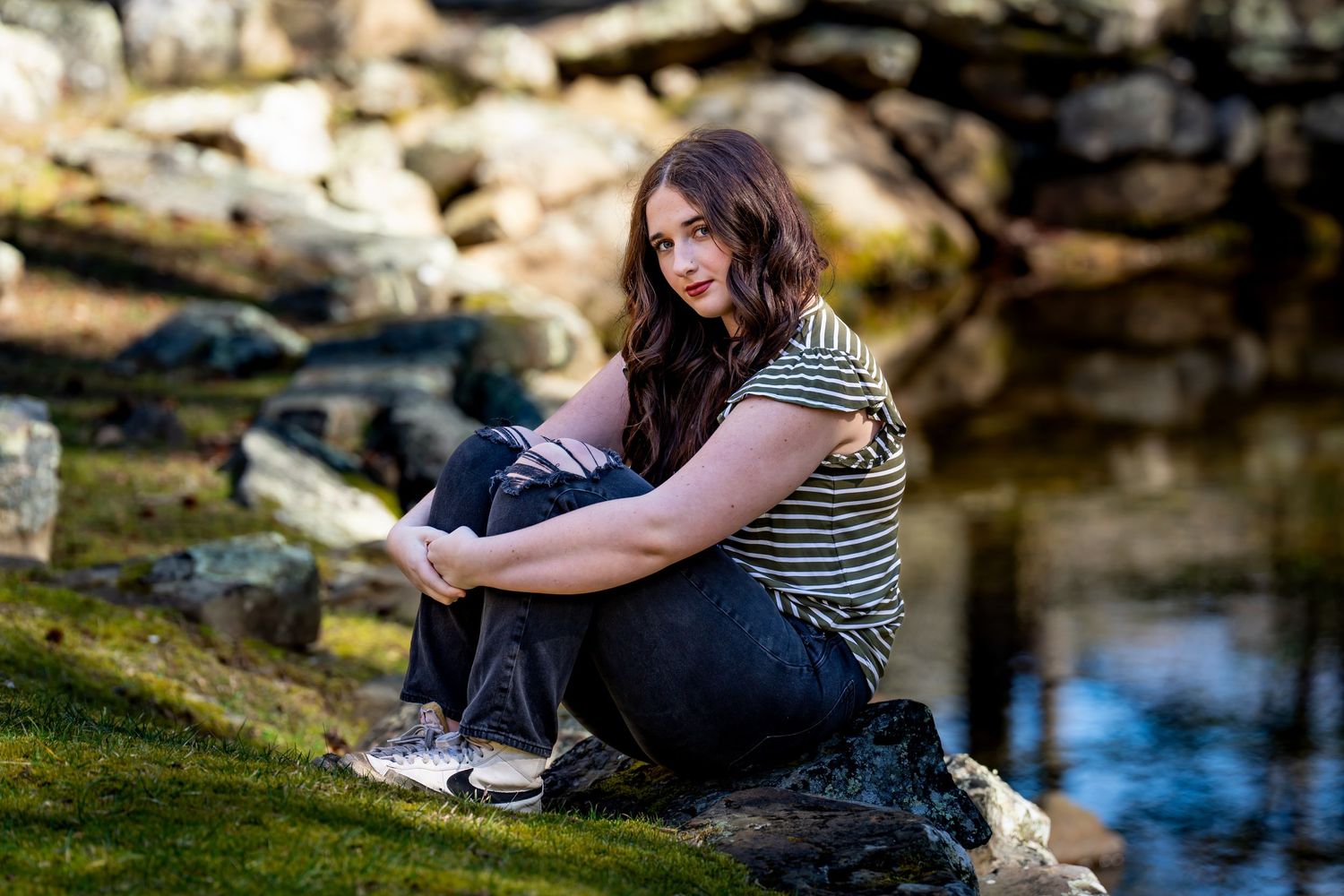 Lifestyle portraits by a waterfront showing casual poses on rocky terrain.