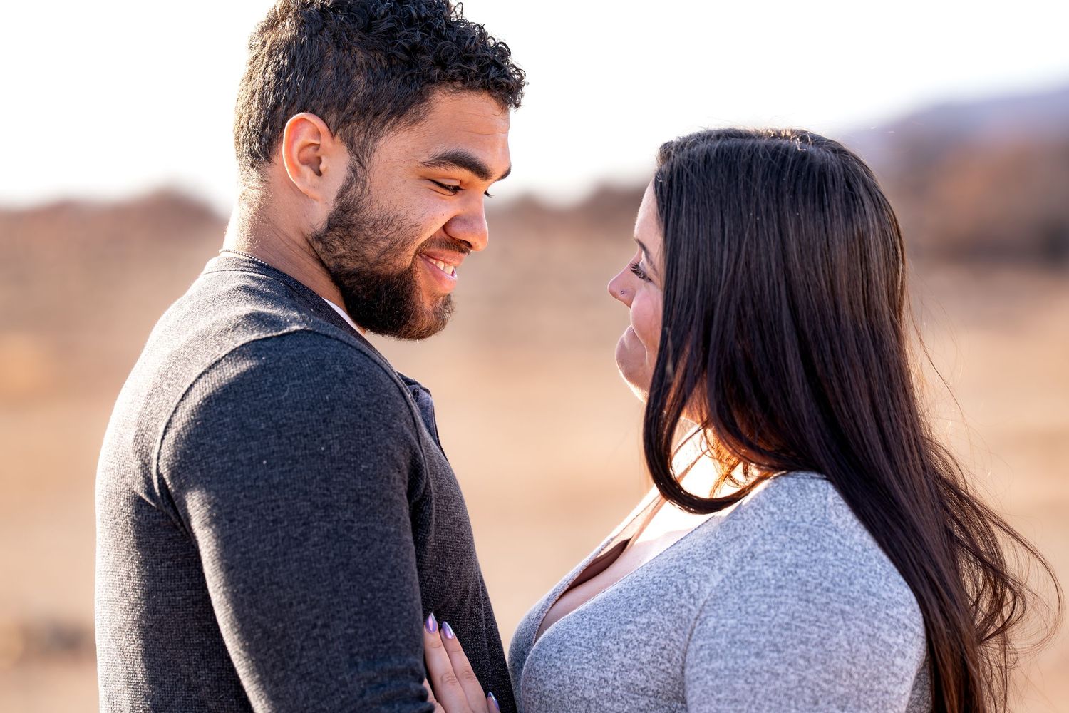A romantic couple embraces and shares tender moments during a sunset engagement photo session in nature.