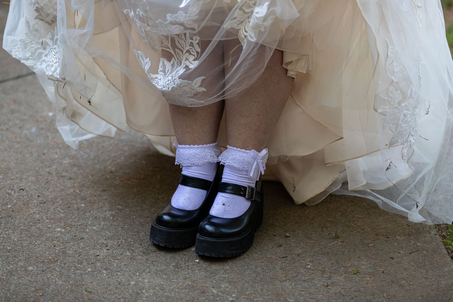 Detail shot of white dress hemline and black mary jane shoes with white socks.